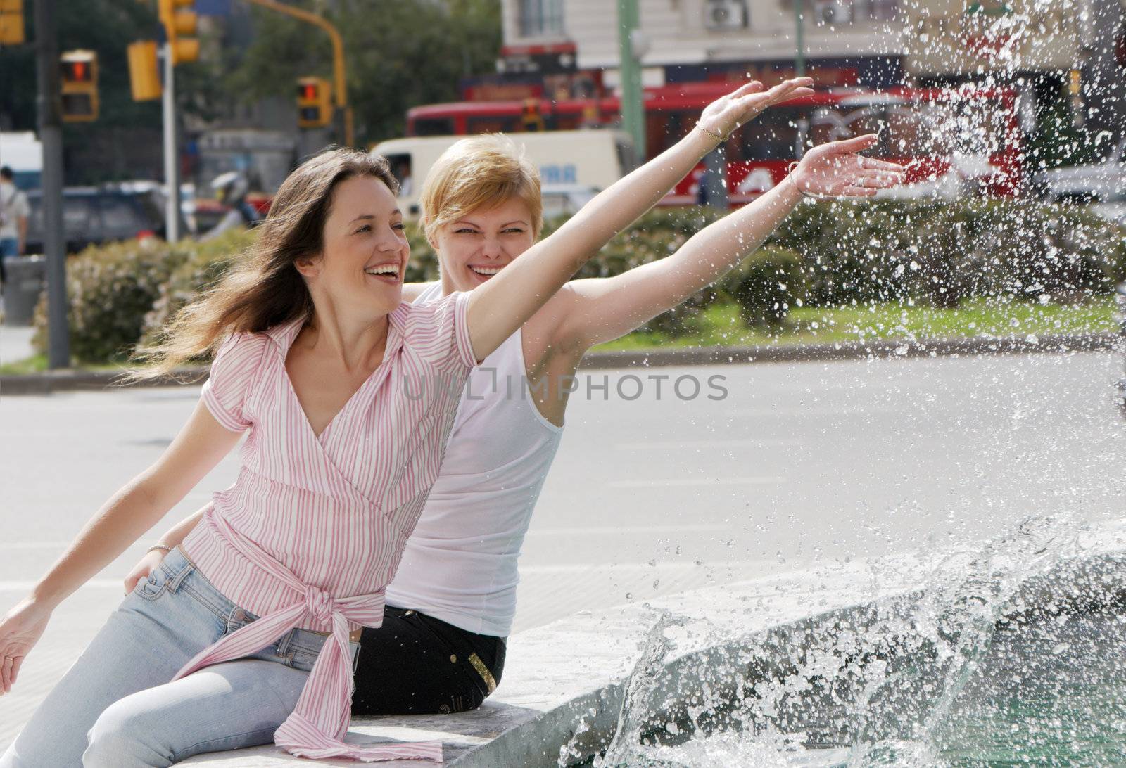 Two emotional girls near a fountain