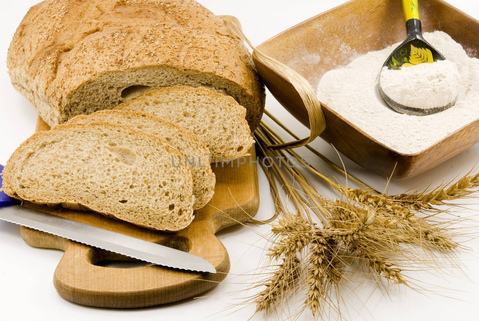 
Loaf of bread cut, knife , flour and  the stem of wheat 