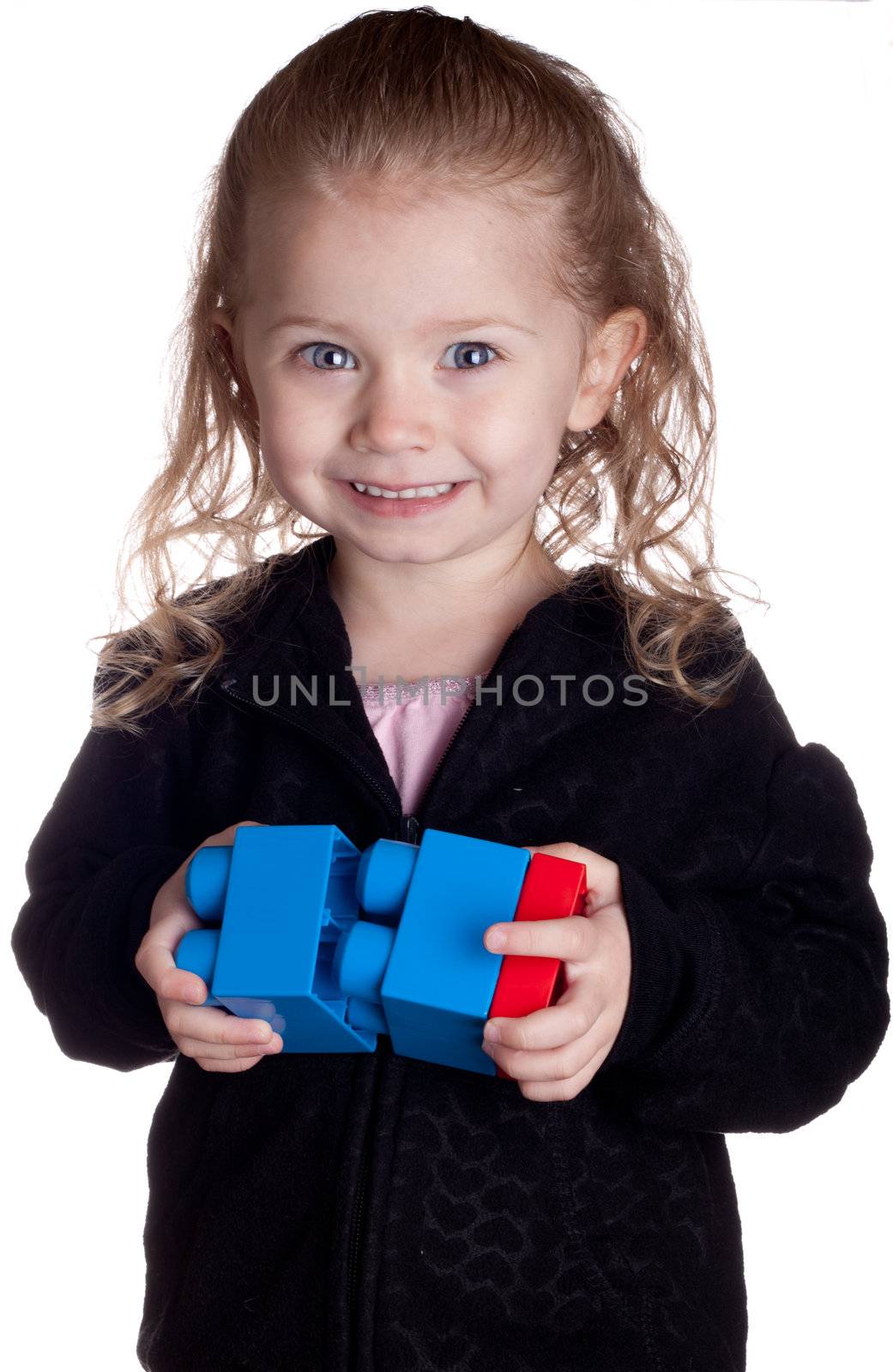 A cute girl is playing with her plastic blocks.  She is a future engineer or construction worker.
