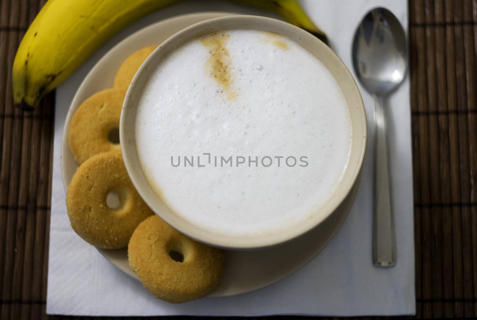 Breakfast with a cup of cappuccino with four biscuits and a banana