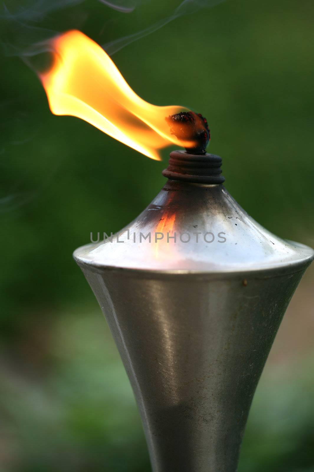 Lit torch with orange flame in garden used as mosquito repellent
