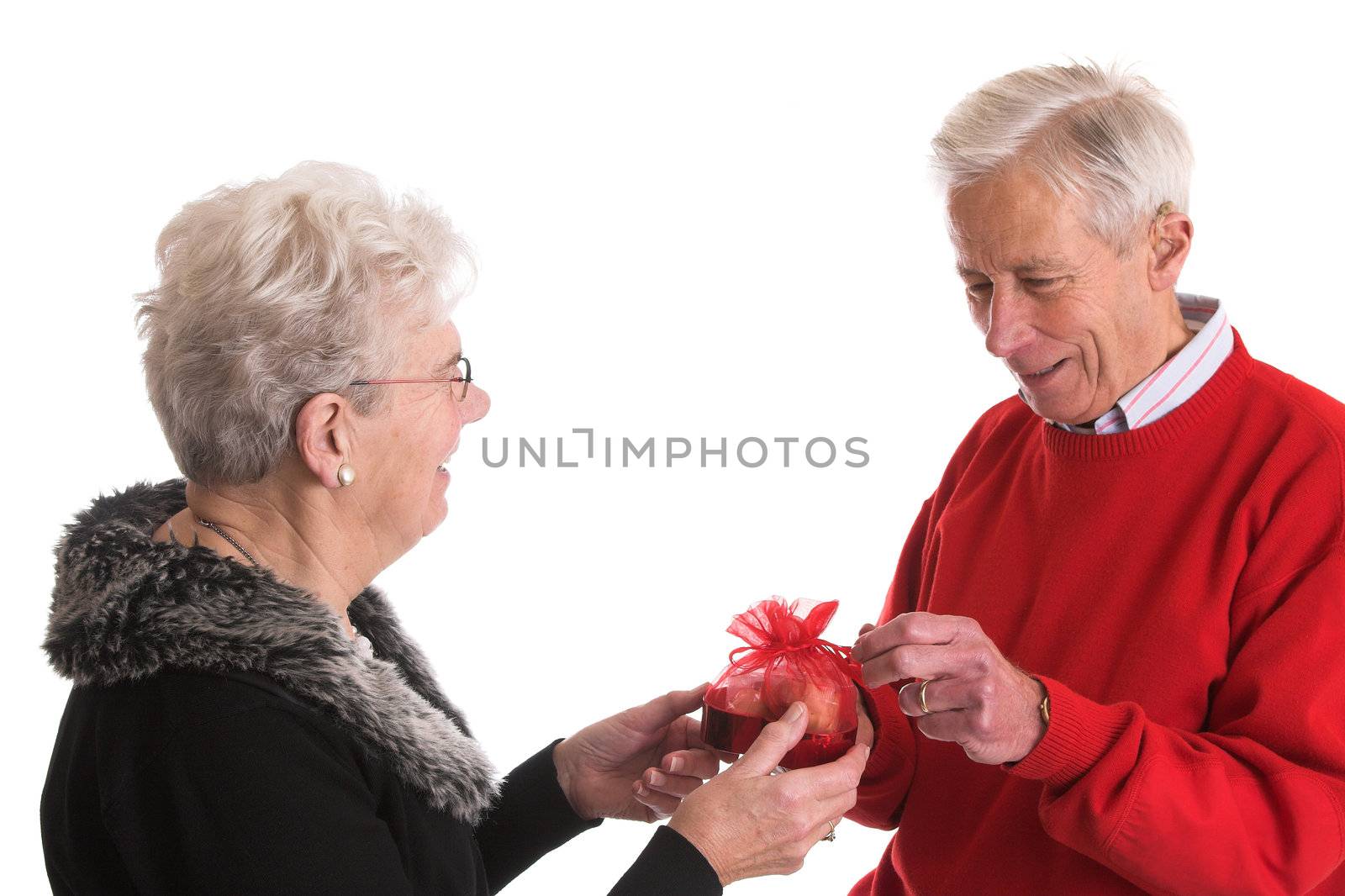 Senior couple where the woman is giving her husband a box of chocolate for valentine