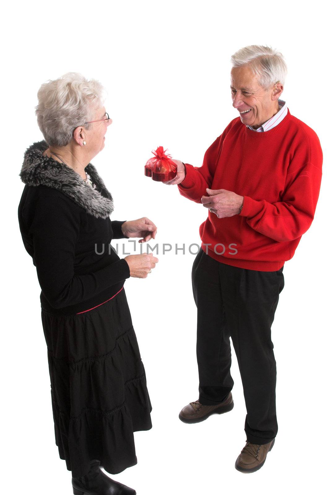 Elderly man giving his wife a box of valentine chocolate with a big laugh