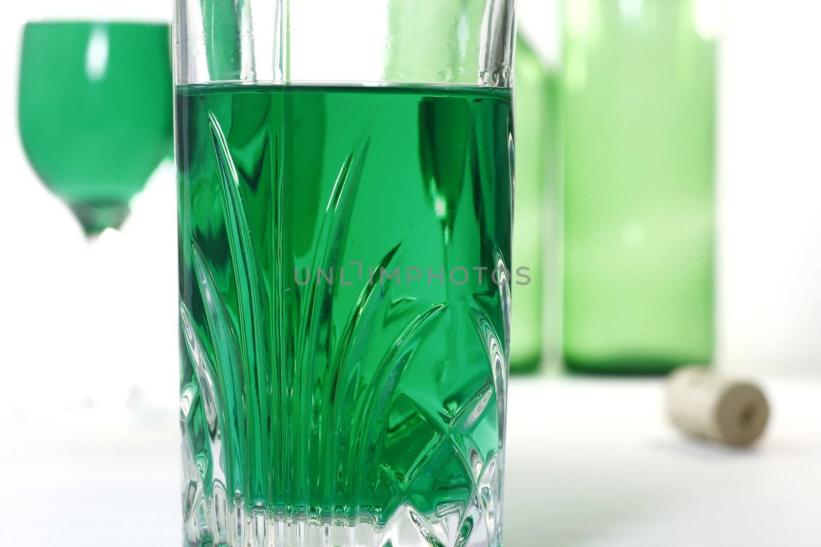 Glass with green wine and green wine background