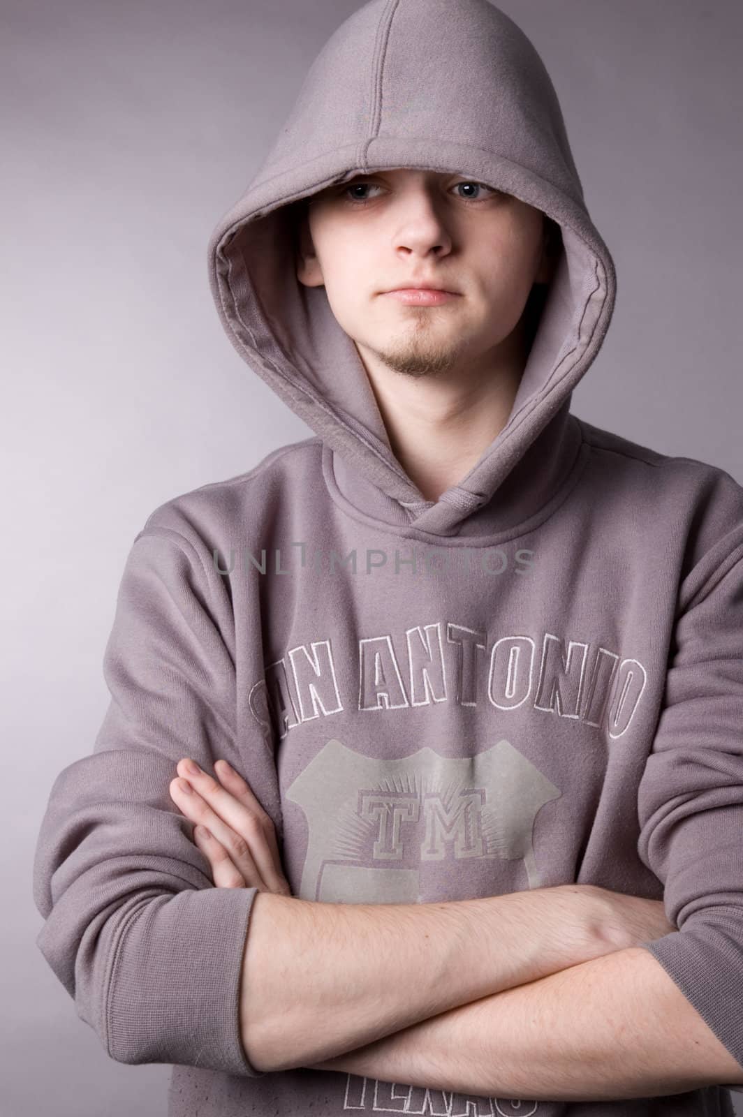 The young guy in a hood in studio on a grey background