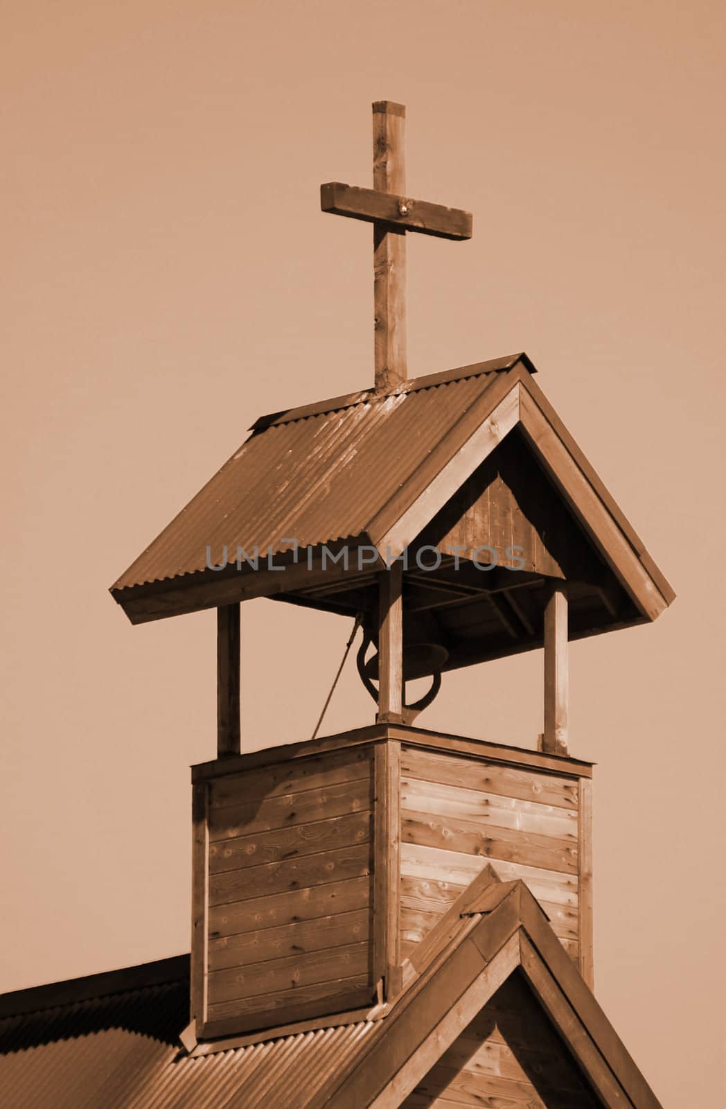 Sepia toned image of old wooden church in New Mexico with hand-hewn cross