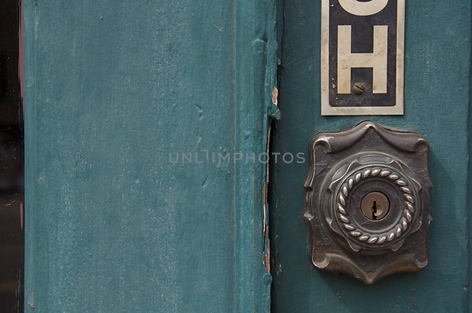 An old green door has a distinct metal lock.