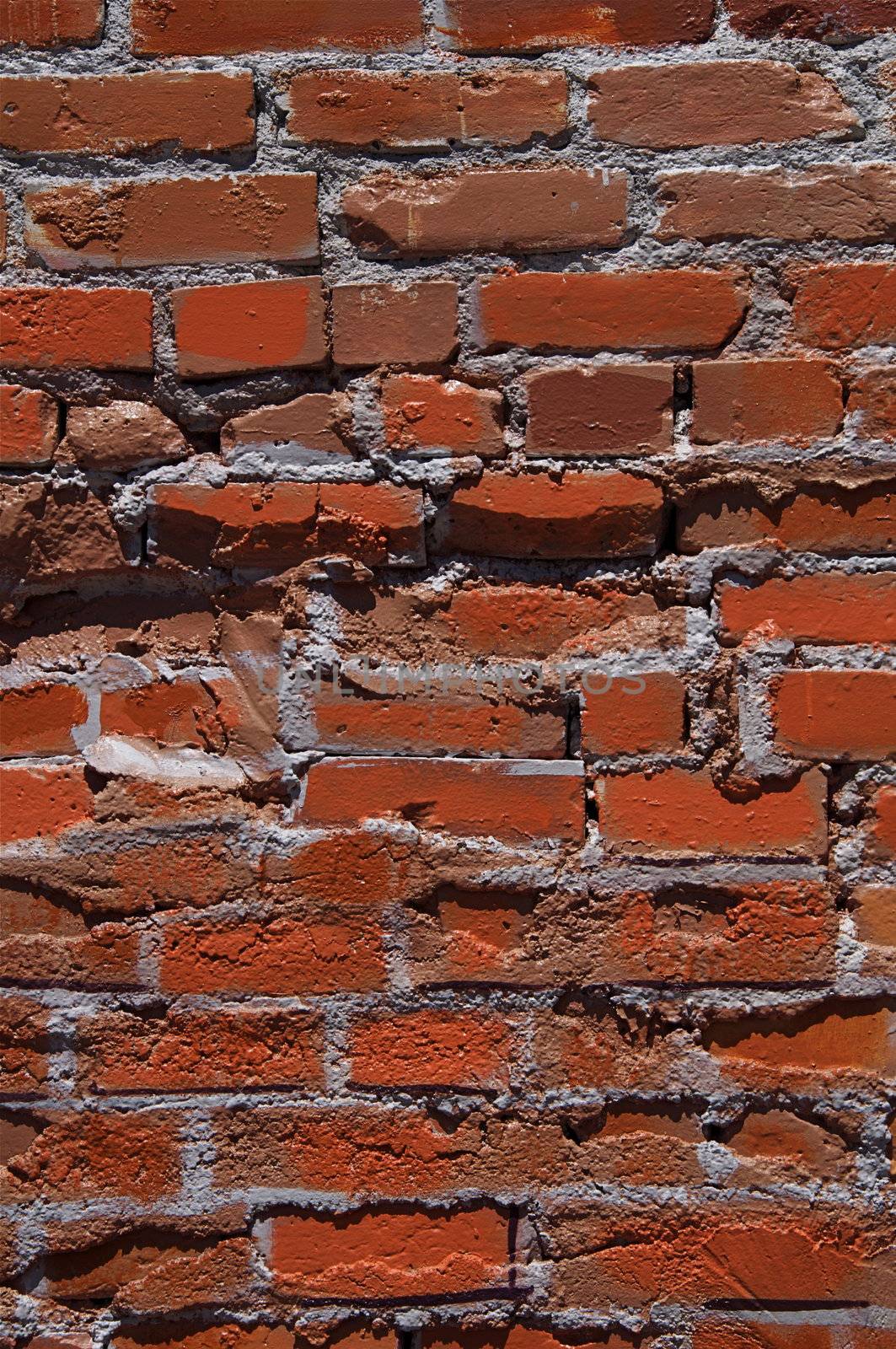 An old red brick wall is rough with uneven texture.