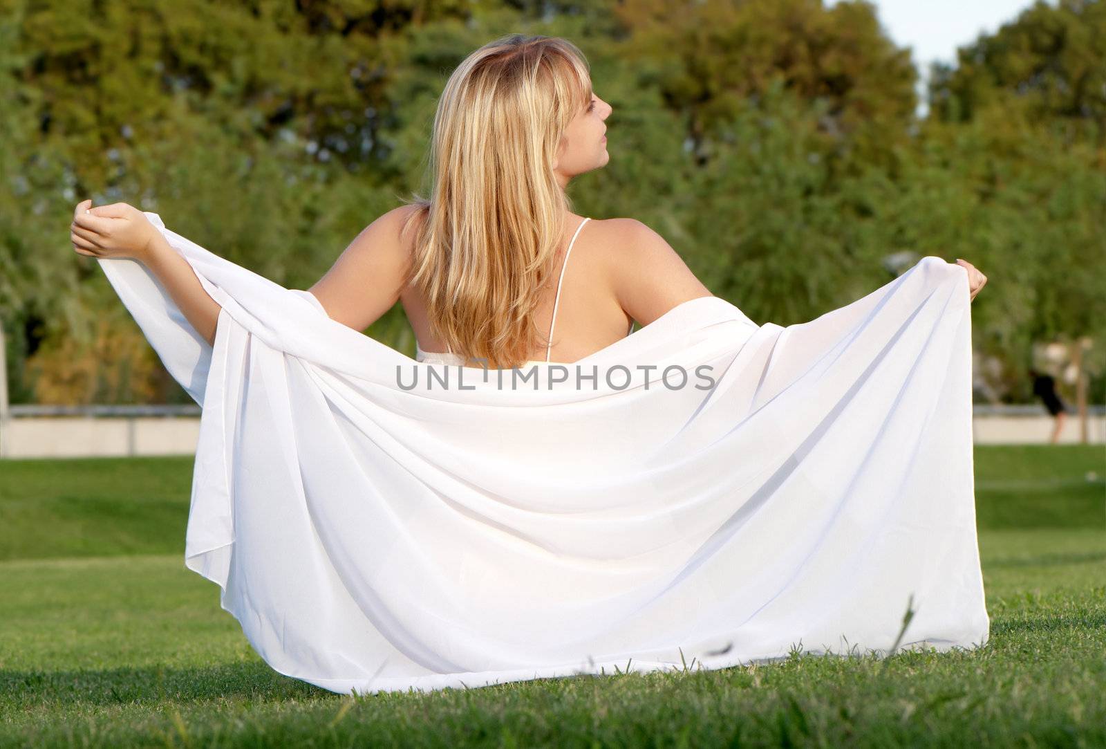 The girl with a shawl sitting on a grass in park