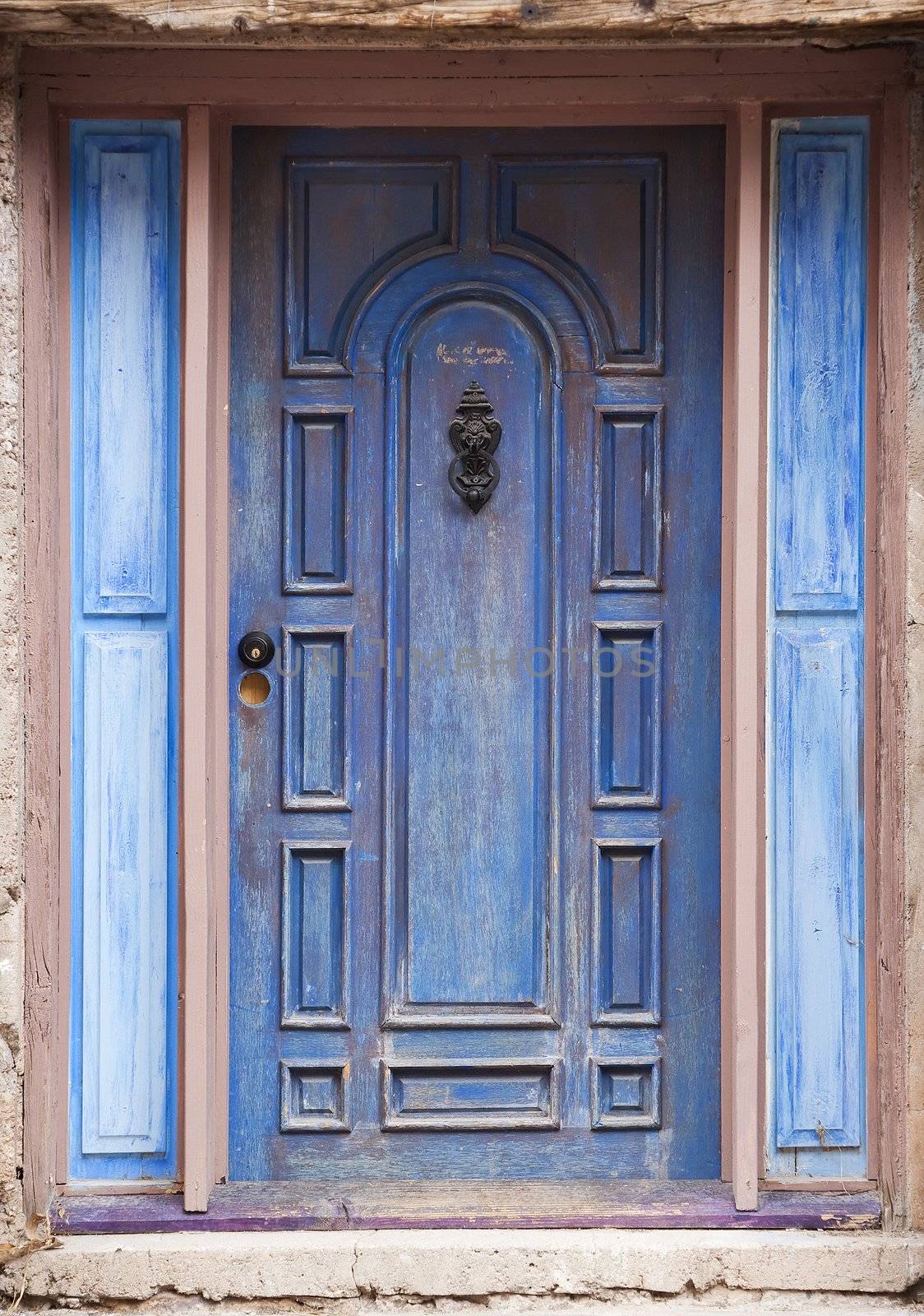 Old peeling blue door with metal knocker