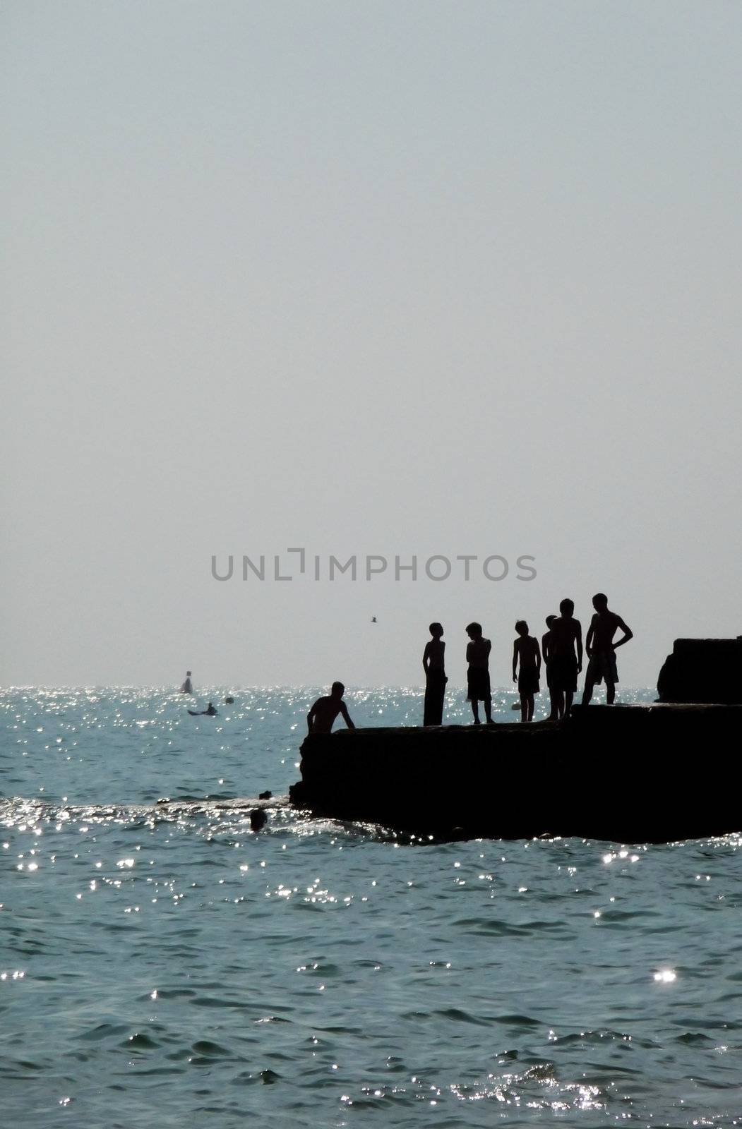 Silhouetted people on a sea defence on the Brighton coast.