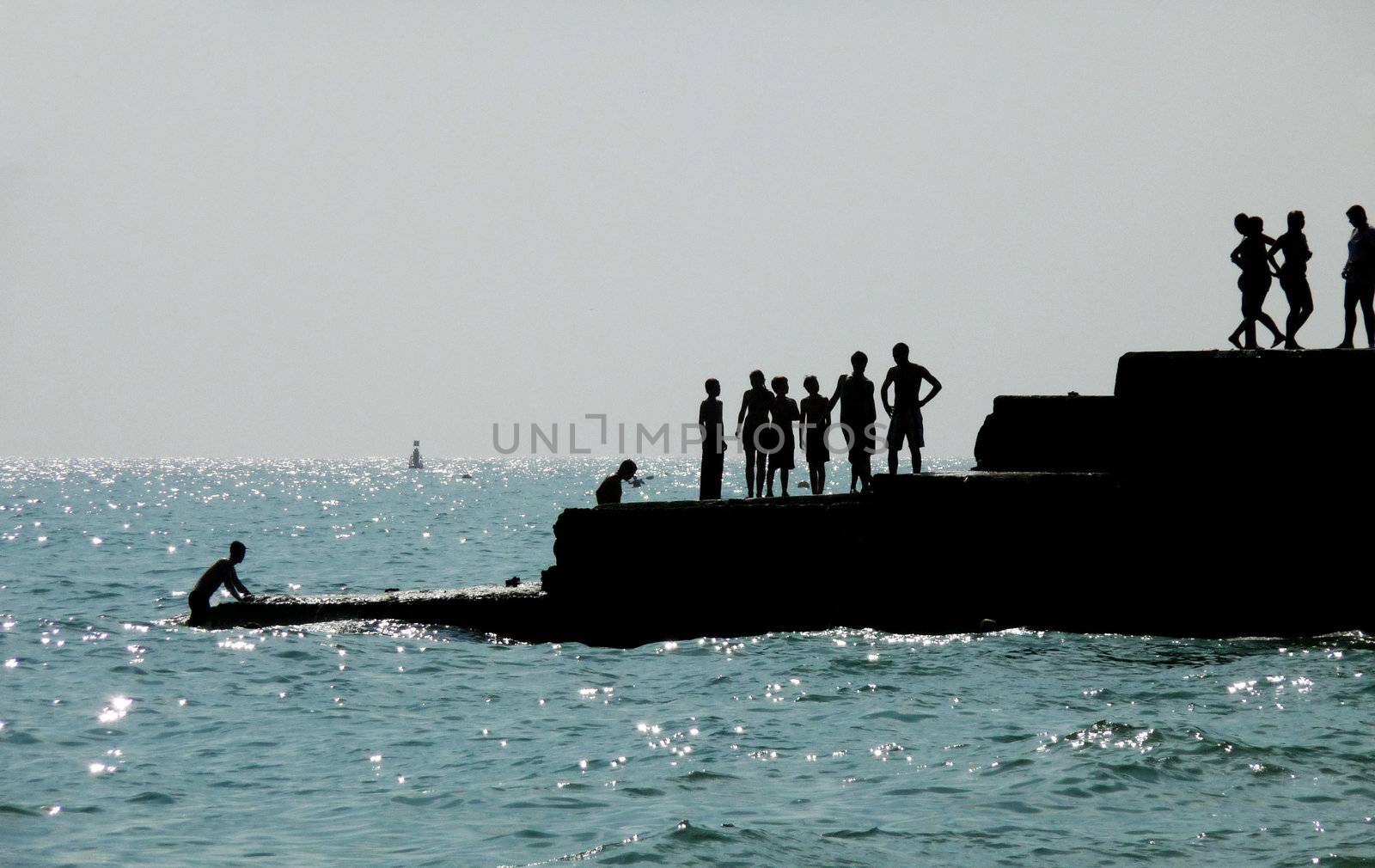 Silhouetted people on a sea defence on the Brighton coast.