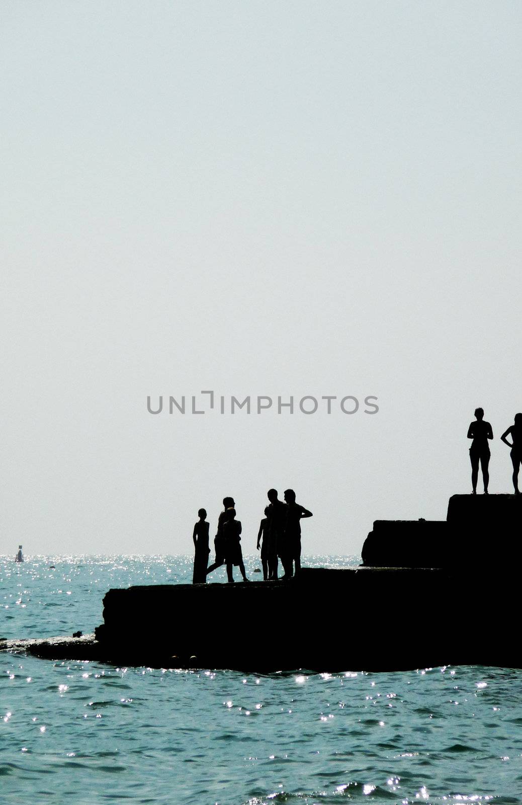 Silhouetted people on a sea defence on the Brighton coast.