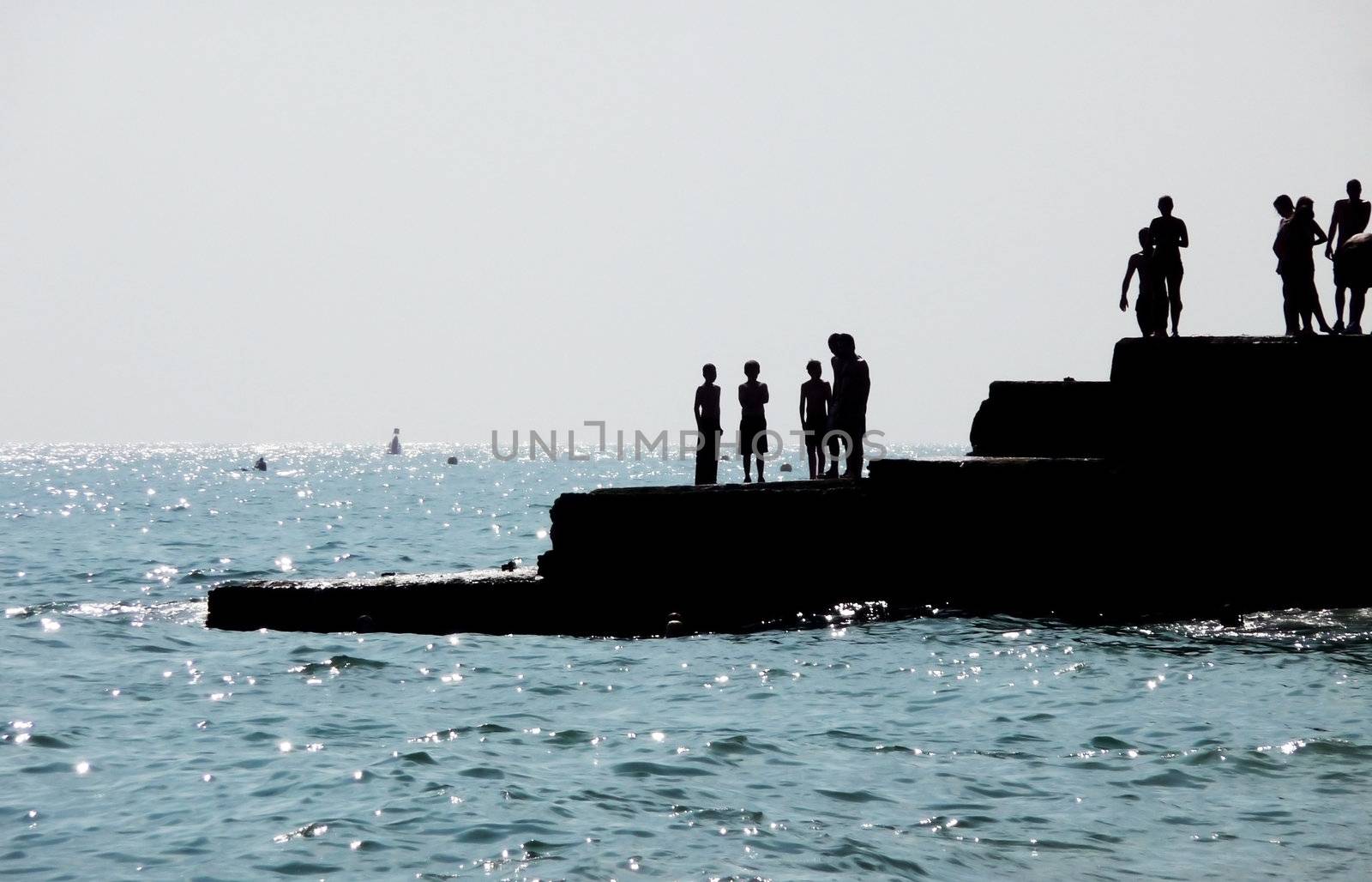 Silhouetted people on a sea defence on the Brighton coast.