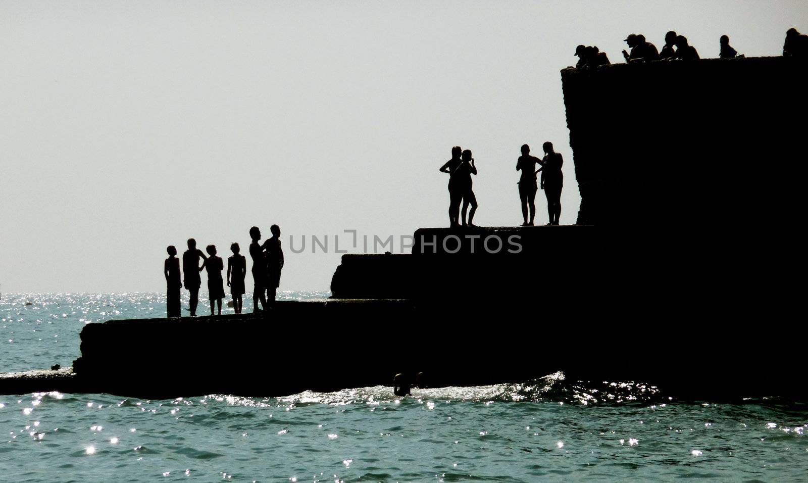 Silhouetted people on a sea defence on the Brighton coast.