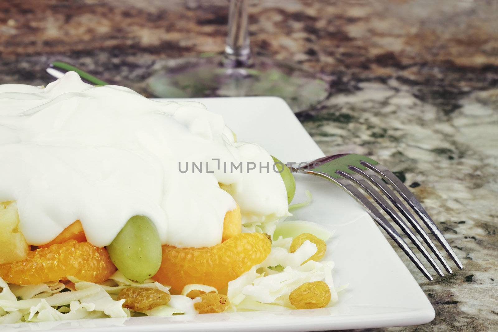 Fruit & Edam salad. A bed of shredded cabbage layered with grapes, mandarin oranges, golden raisins, pineapples, green grapes and edam cheese topped with a creamy sweet sauce of yogurt and sour cream.  
