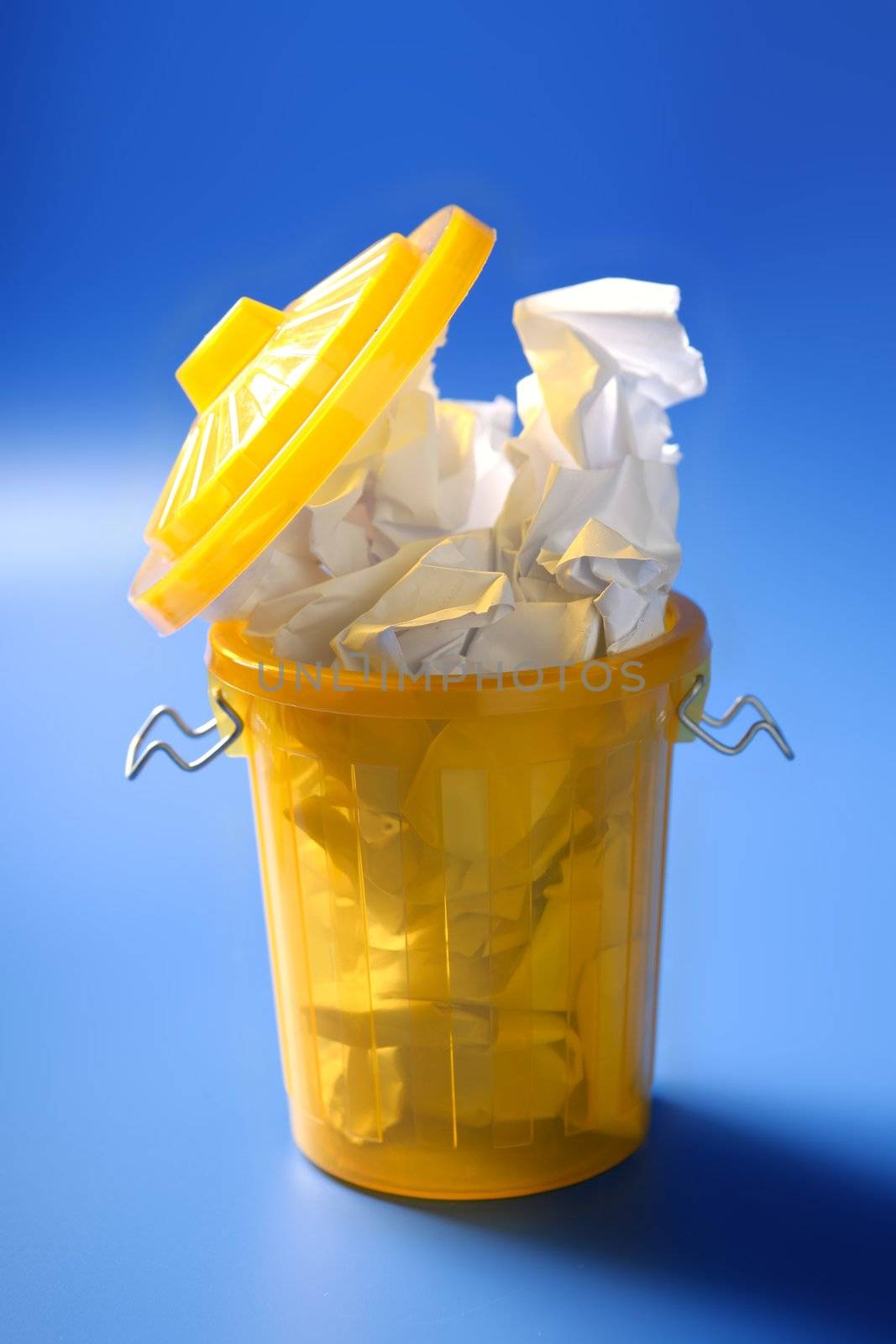 Paper trash in yellow over blue background, business metaphor