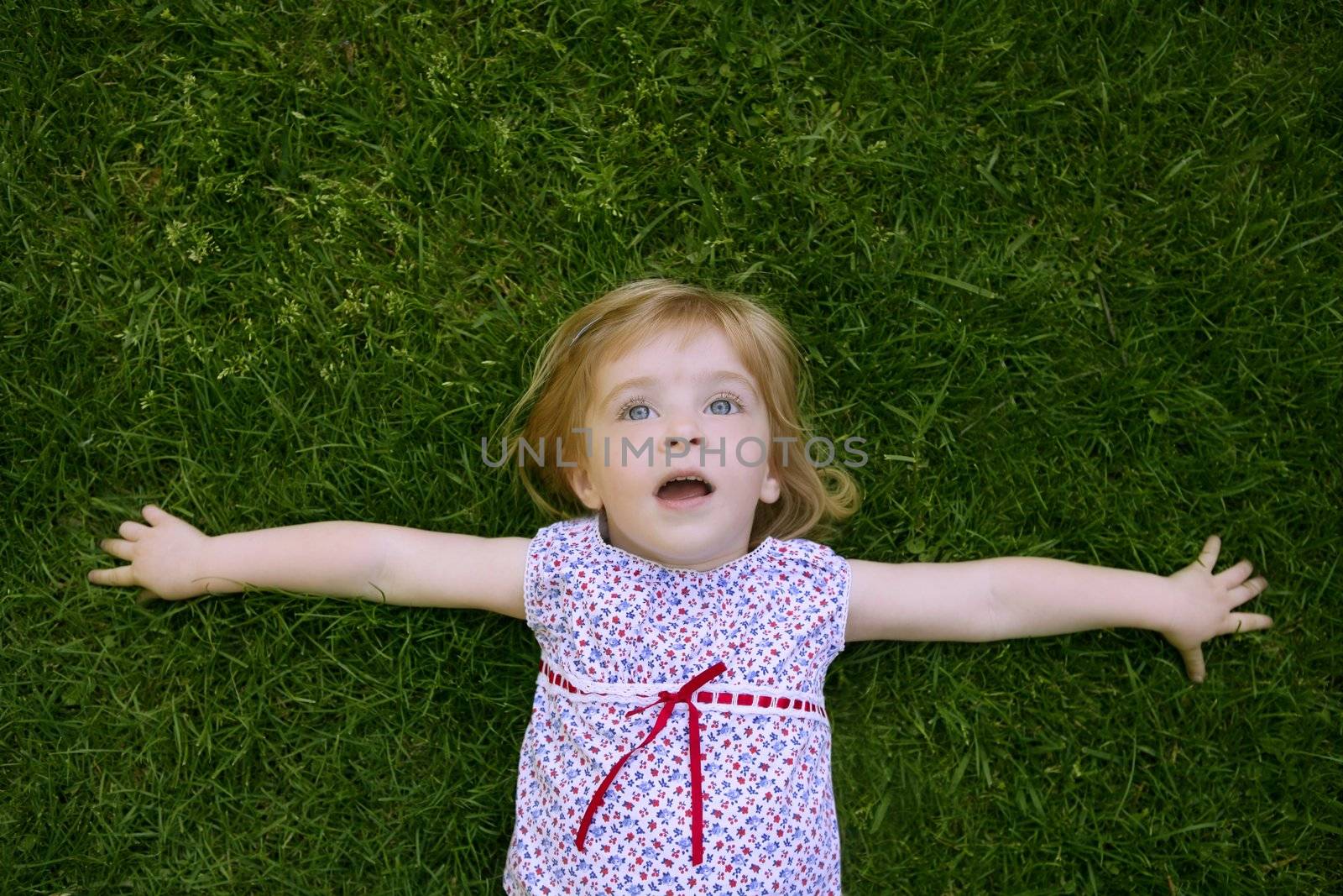 Beautiful little toddler girl happy lying on grass by lunamarina