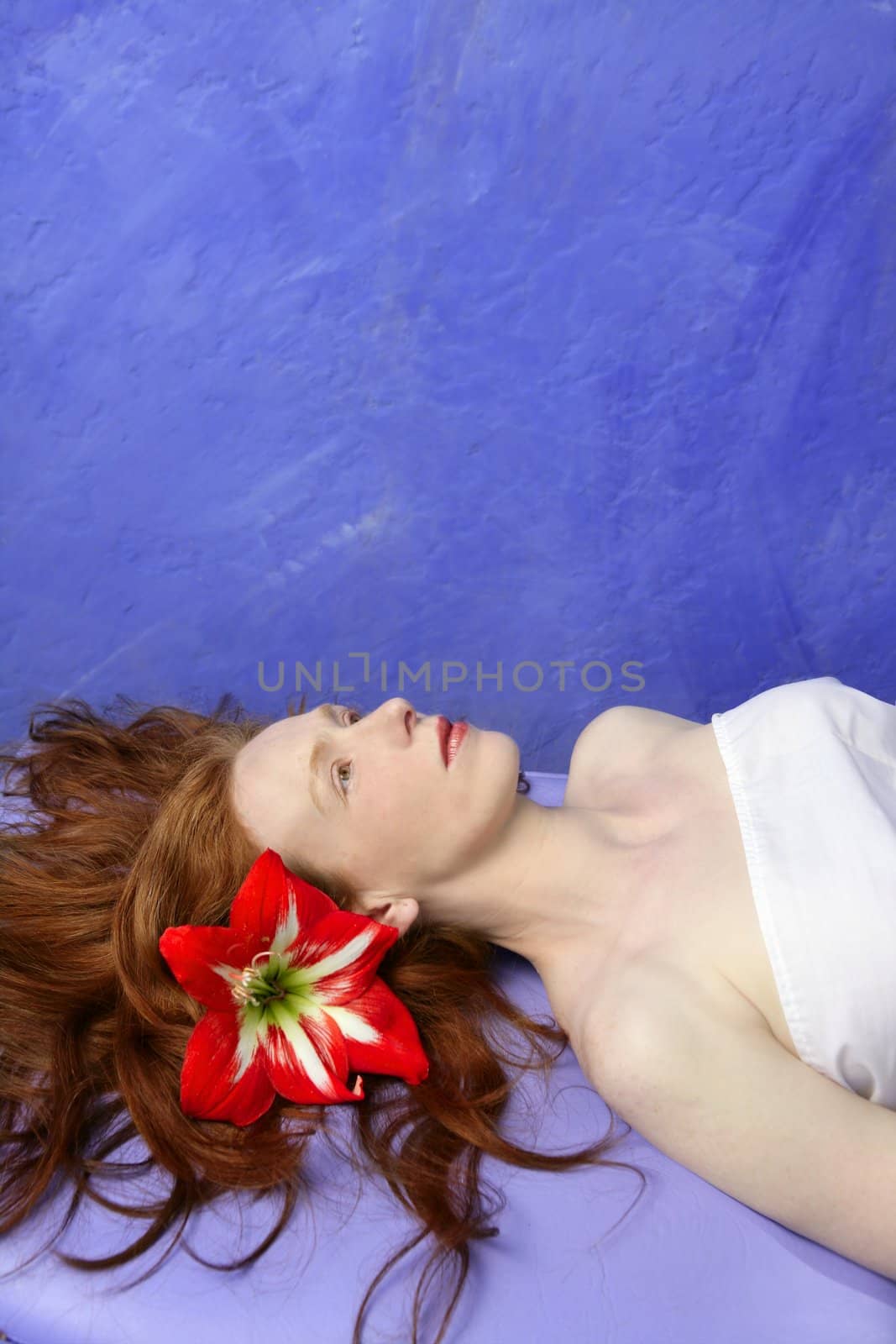 Beautiful redhead woman in a vivid massage blue board, orange flower