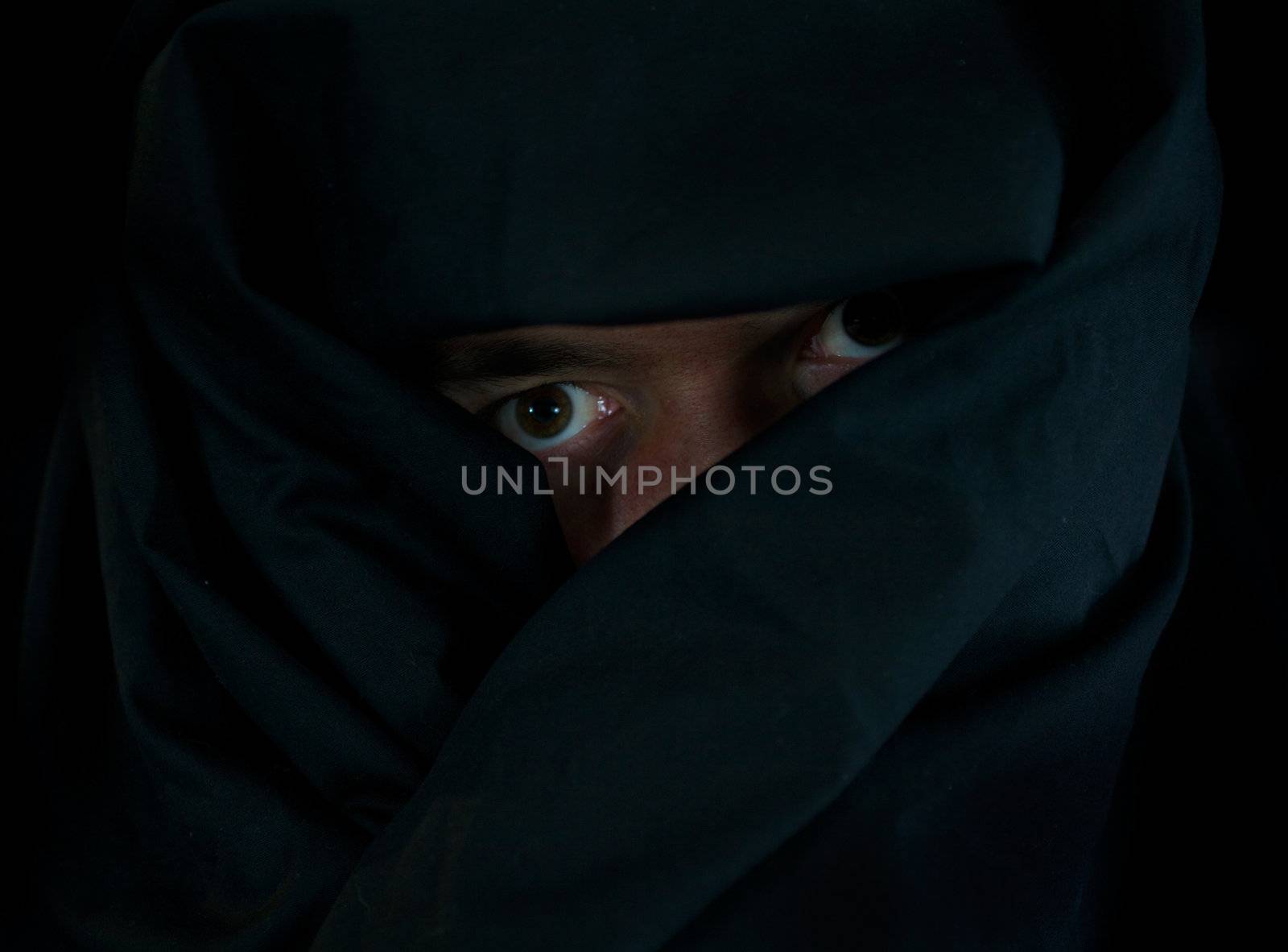 Scary Eyes Behind Black Cloak in the Darkness