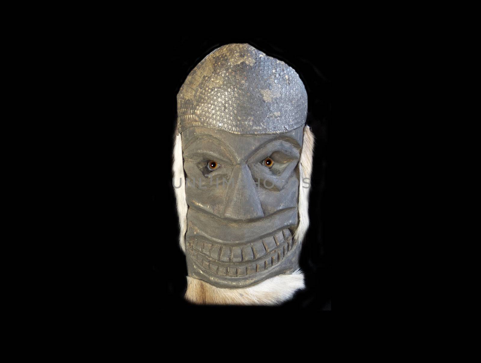 A tiki mask with scary eyes on a black ground