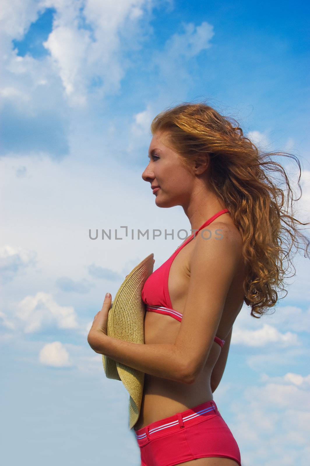 Woman in bikini with flying hair over dramatic sky
