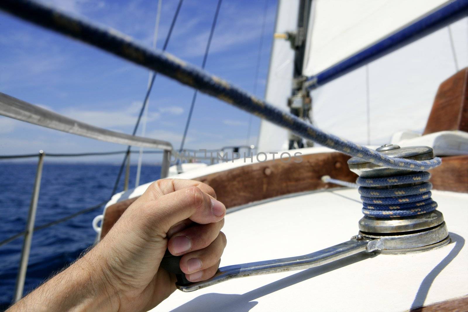 Blue summer water and sky in a sailboat race, sailor man in winch