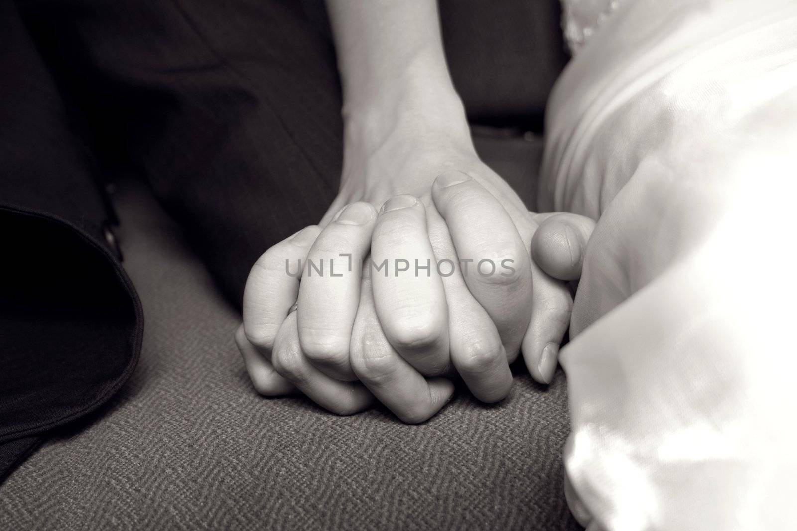 The hands of bride and groom twisted together