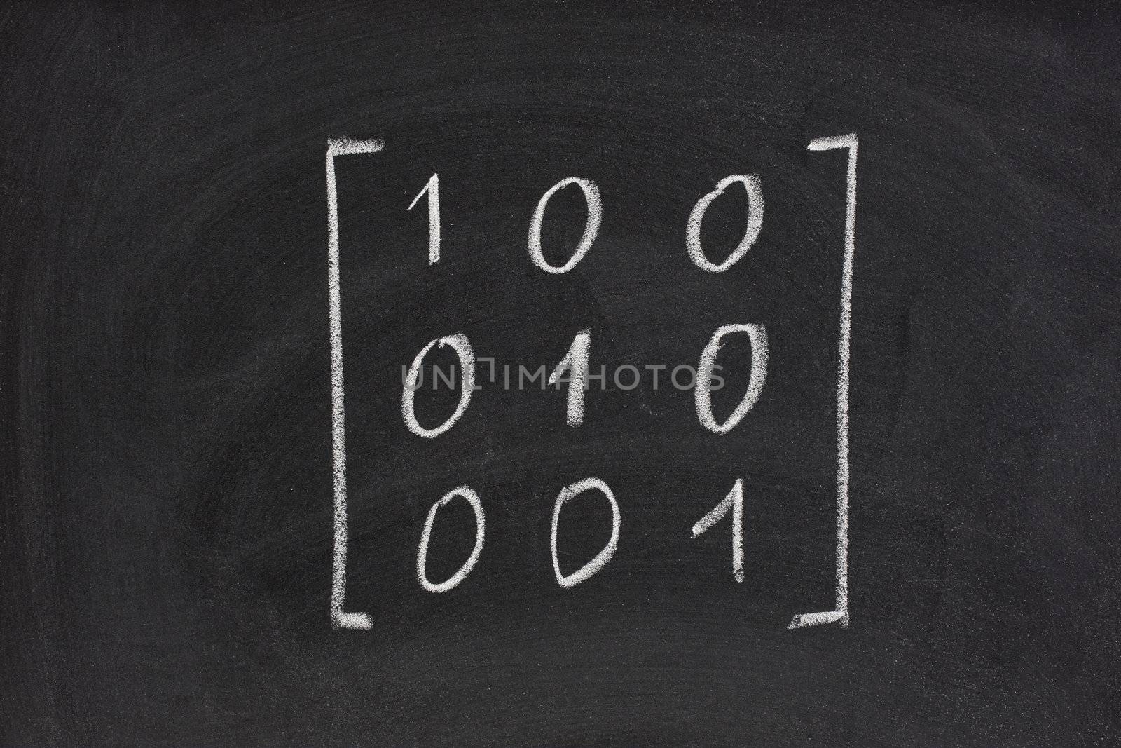 identity matrix with three rows and column handwritten with white chalk on blackboard, eraser smudges texture