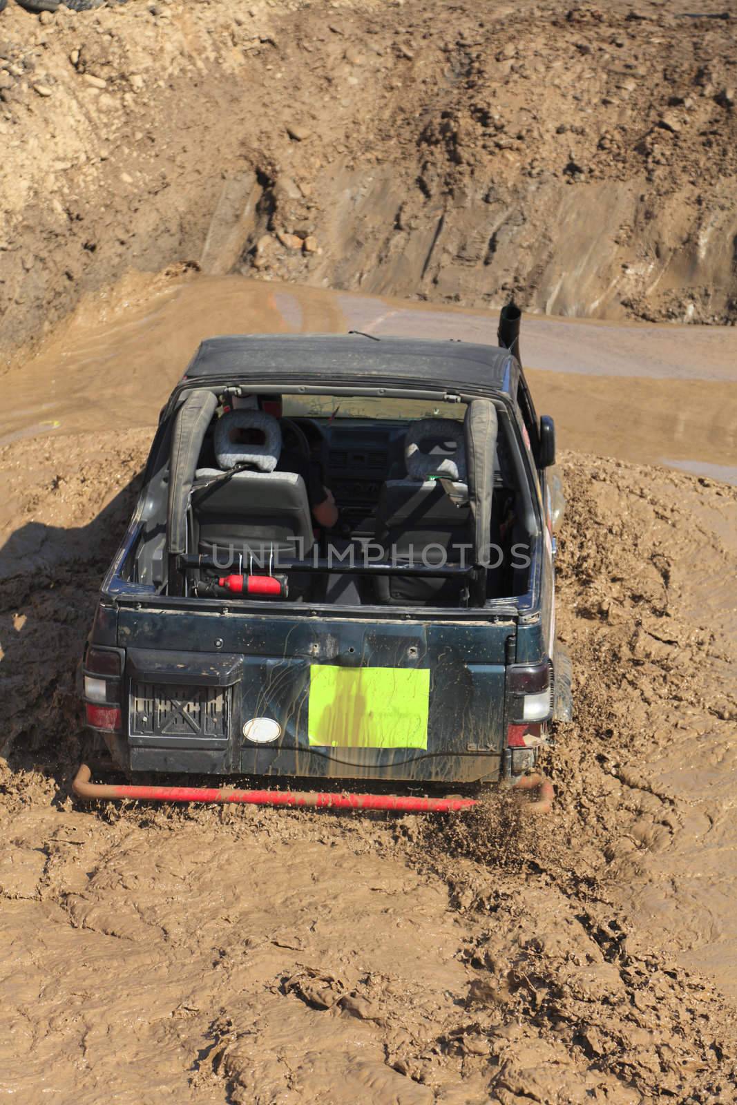 A truck during a tough off-road competition diving in a muddy pool.