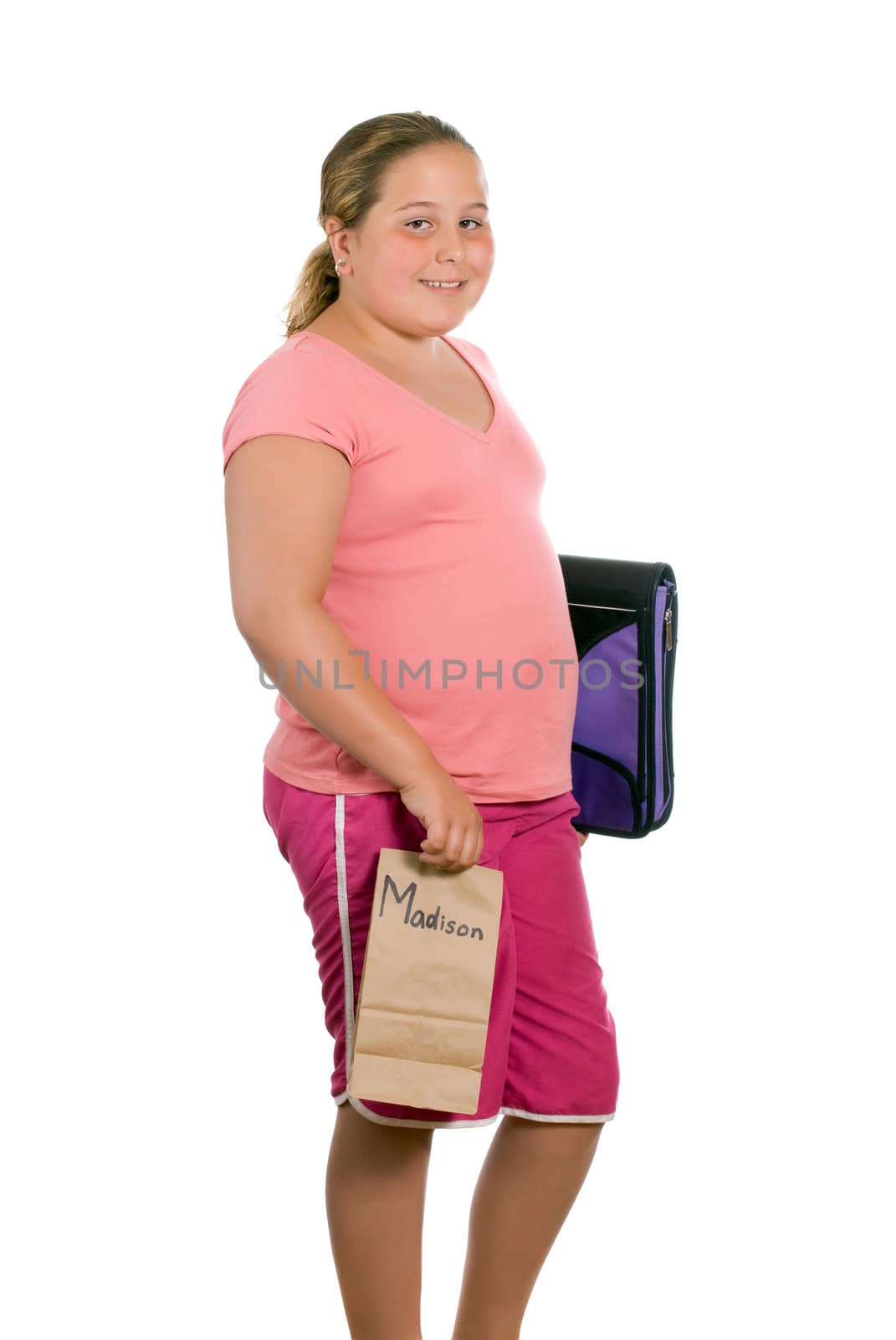 A preteen is holding her school binder and a brown paper lunch bag and is off to school, isolated against a white background - artificial name on the lunchbag