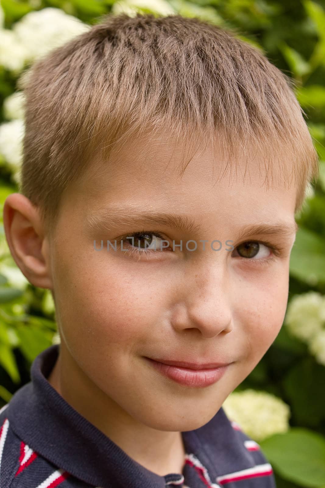 Portret of little smiling boy near flowers outdoors