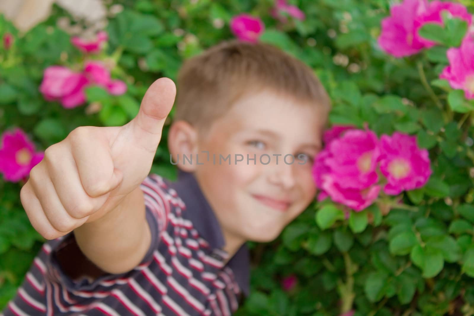 Portret of little smiling boy outdoors with fingers up