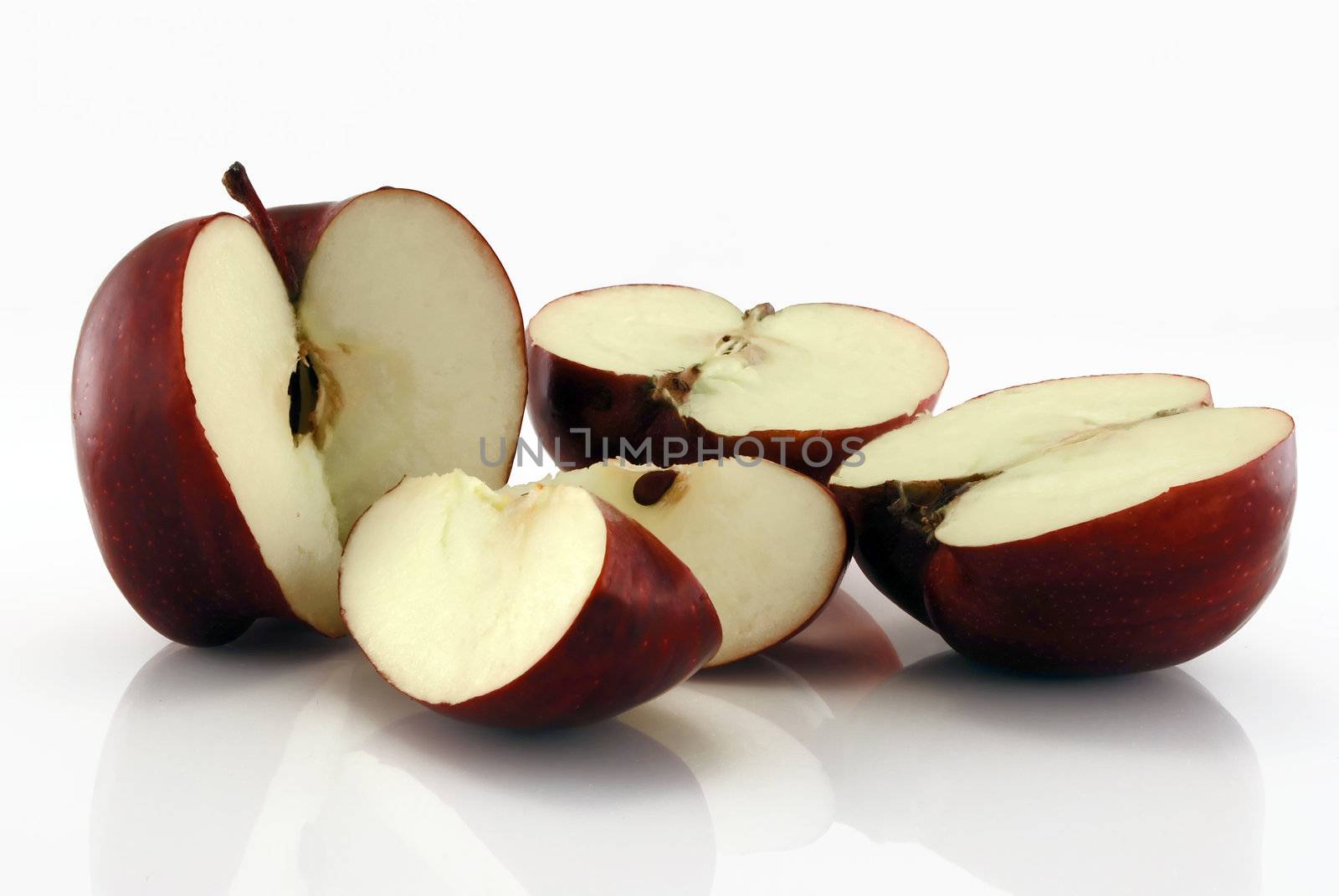 Chopped red apples on reflective background against white