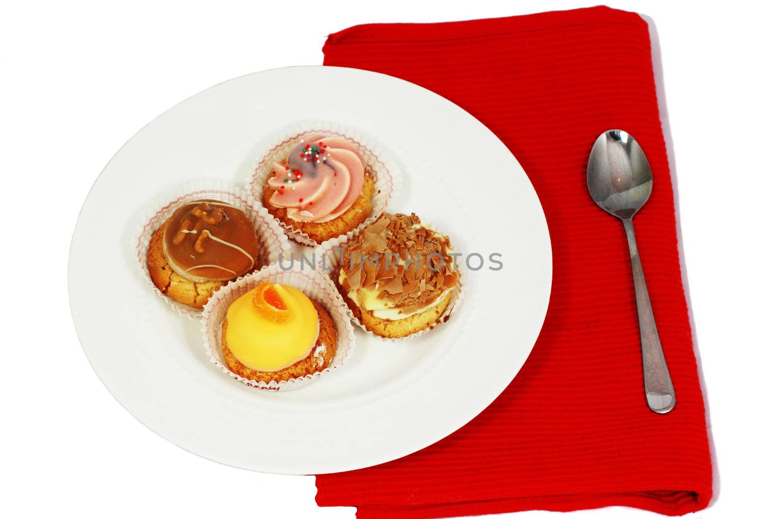 four different muffins on white plate with spoon on red table napkin