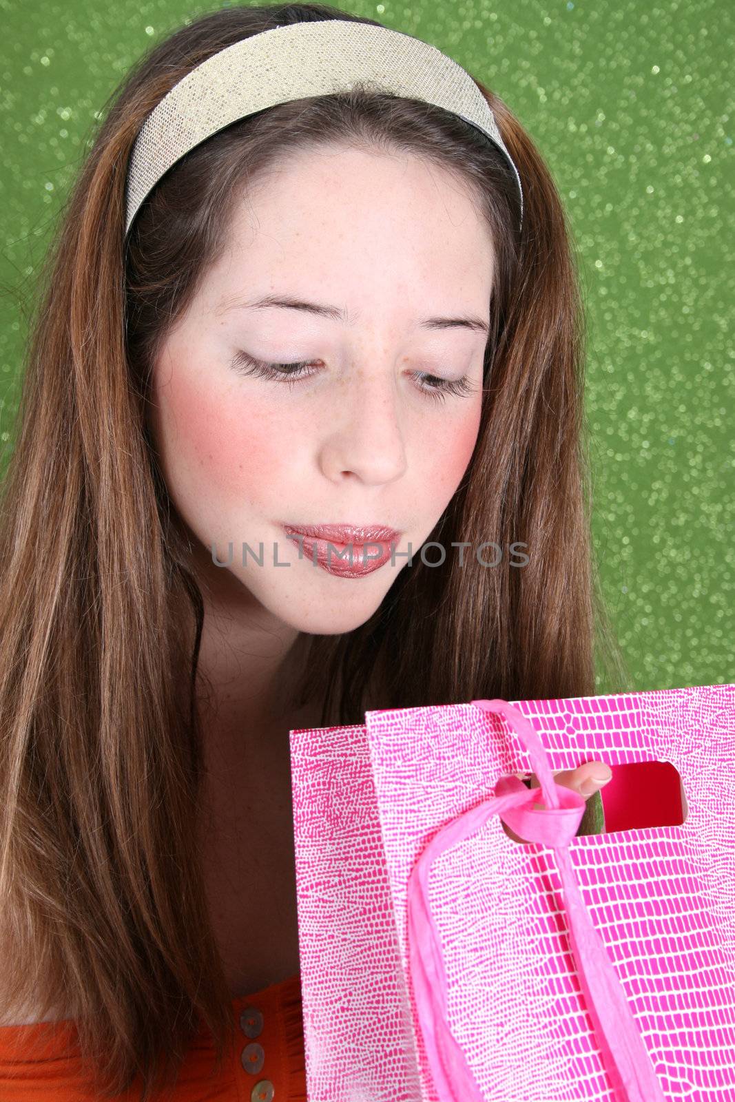 Brunette teenager peeping into a pink gift bag