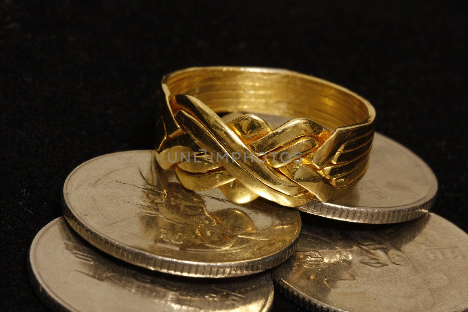 Gold Puzzle ring with coins in a black velvet background.