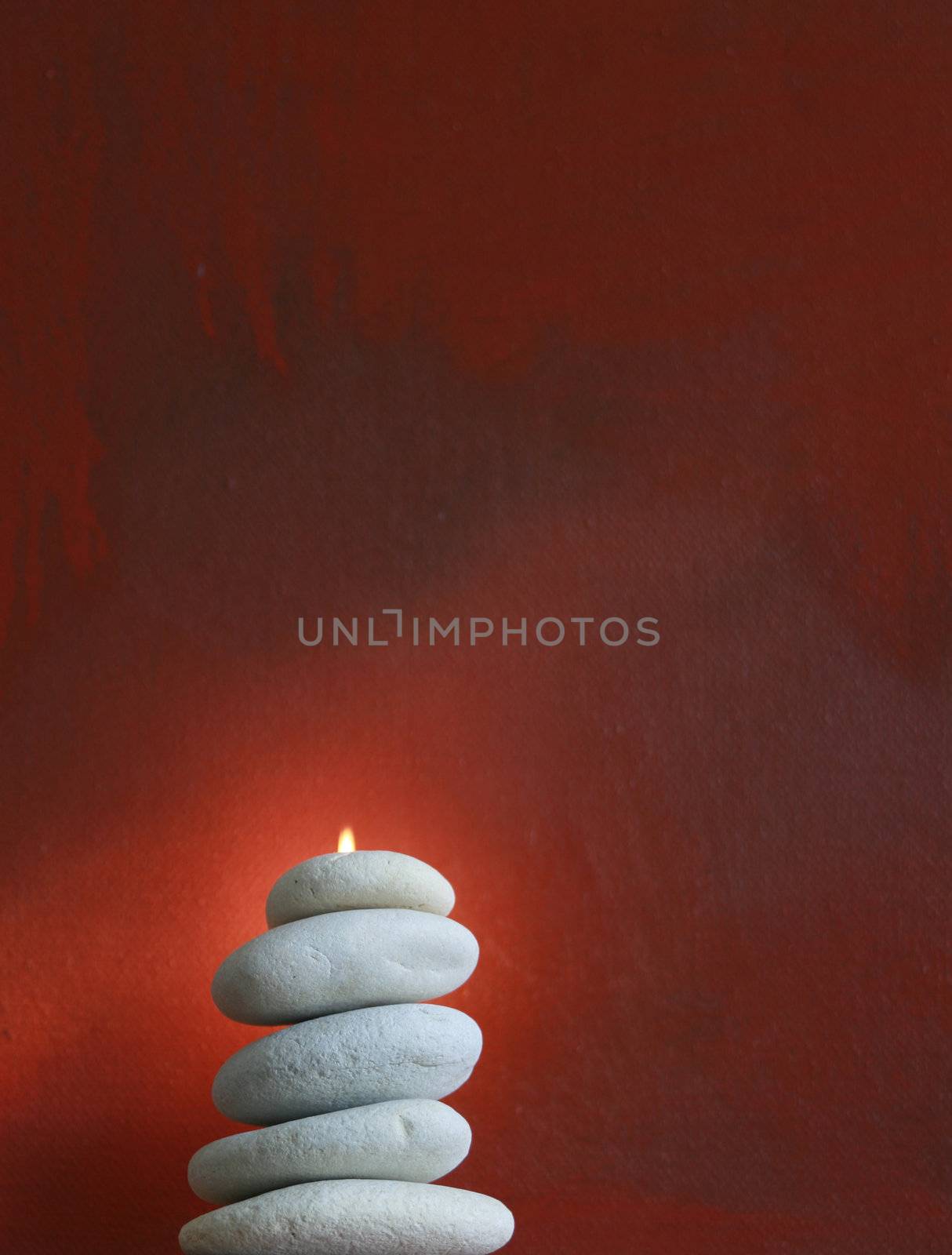 A stack of light grey pebbles stacked on top of eacj other set against a red 'grunge' styled oil painted canvas background. Pebbles have a small flame emerging from its top.