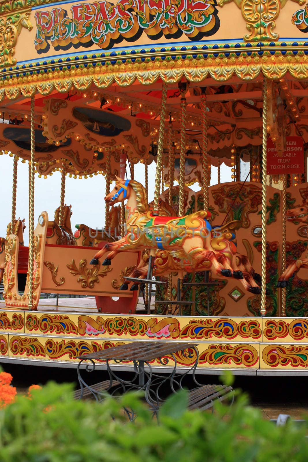 A colourful fairground carousell ride with colourful carved horses, located on the pier at Weymouth, Dorest UK. 