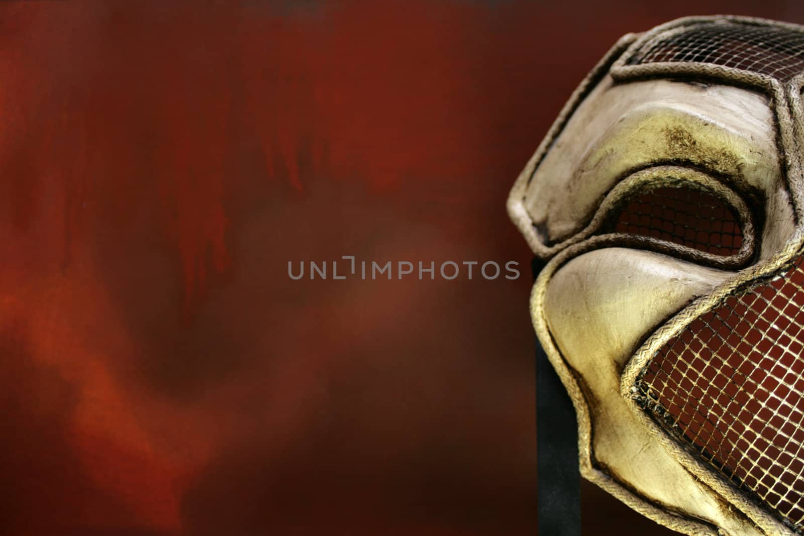 A hand made Venetian mask set to the right of a landscape image on a red grunge styled background. Copy space available.