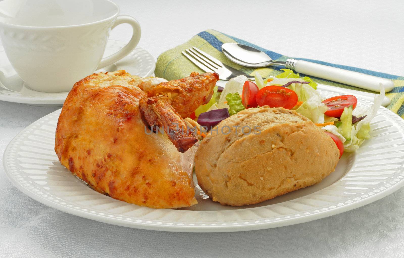 Delicious chicken served with fresh roll and salad.