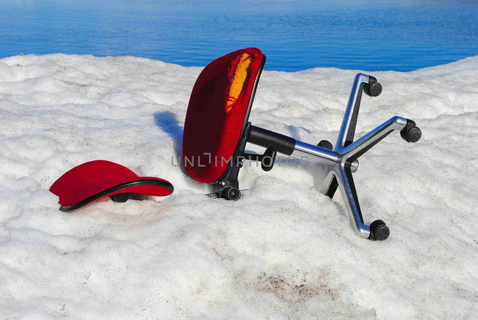 An abandoned office chair lying in snow.