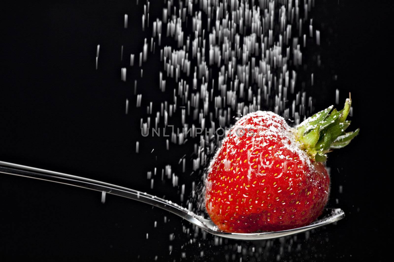 icing sugar falling on a strawberry on a spoon