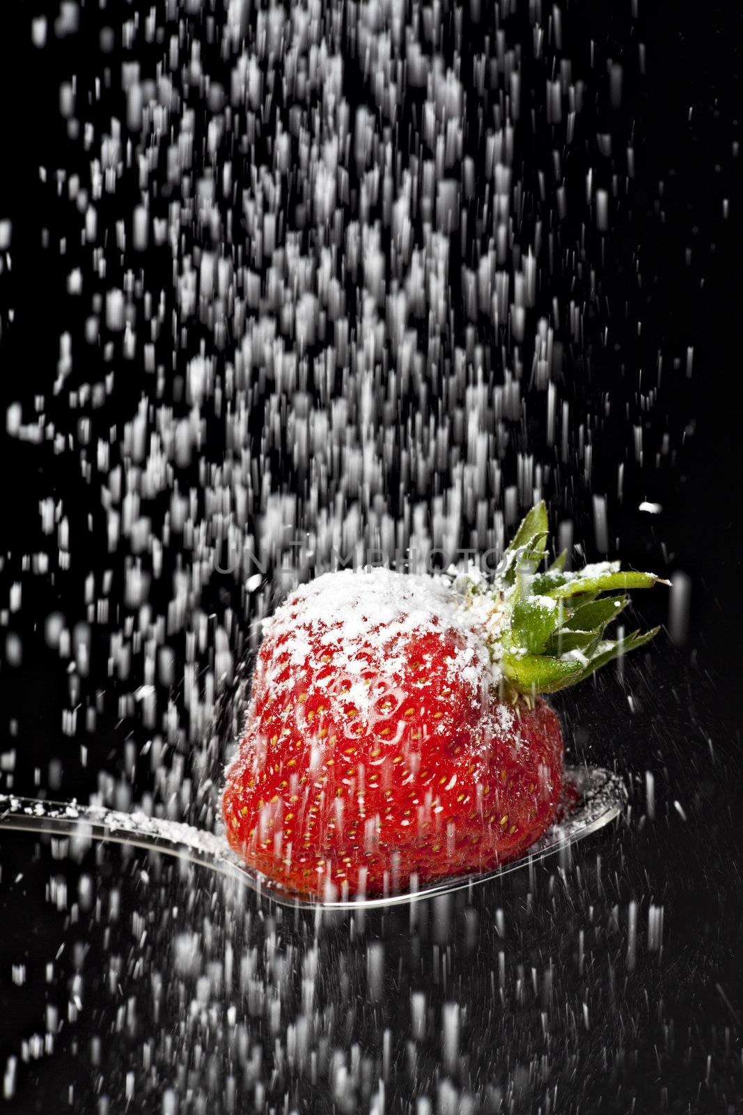 icing sugar falling on a strawberry on a spoon