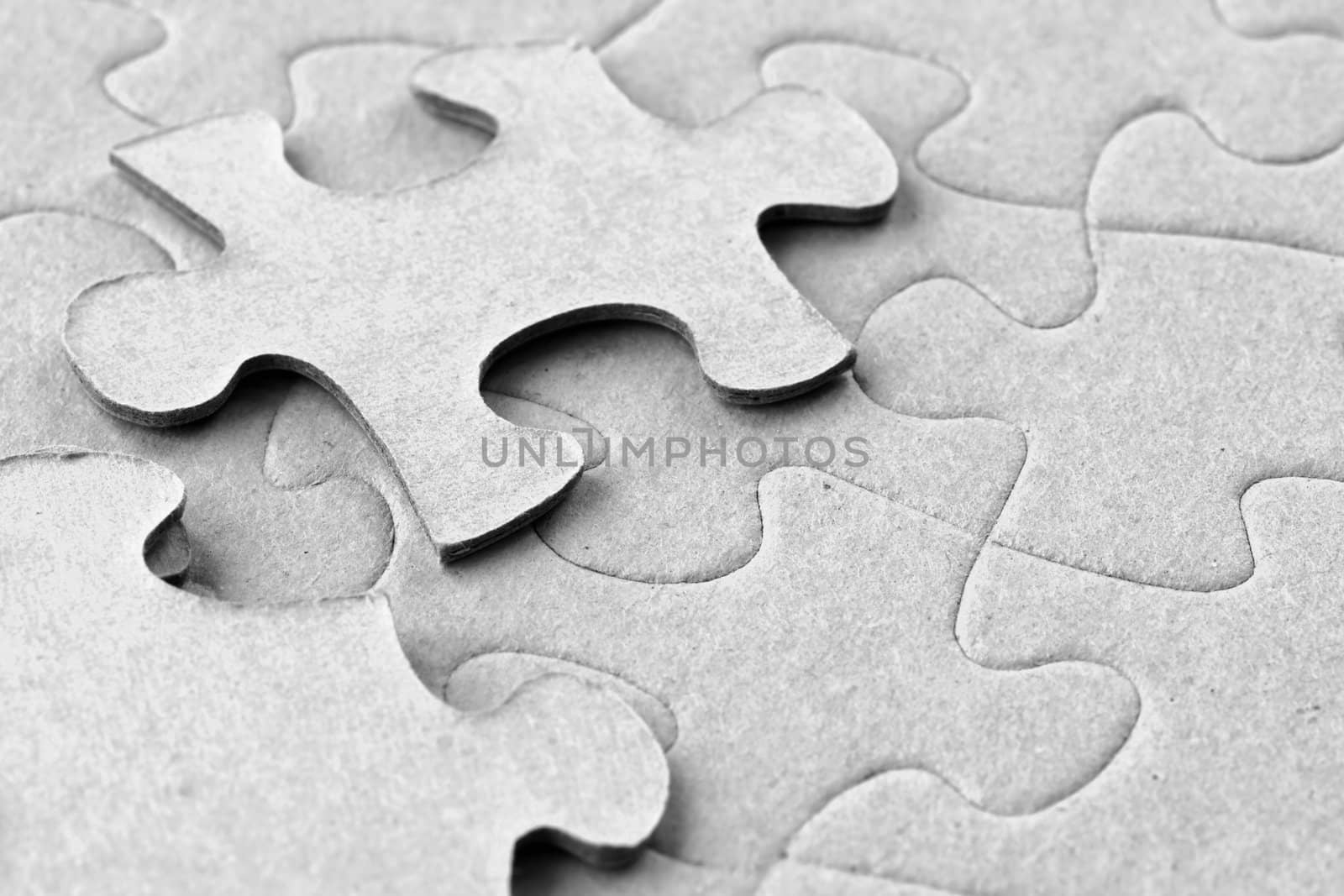 Photograph of blank grey cardboard jigsaw puzzle with two floating pieces on top, great material details.