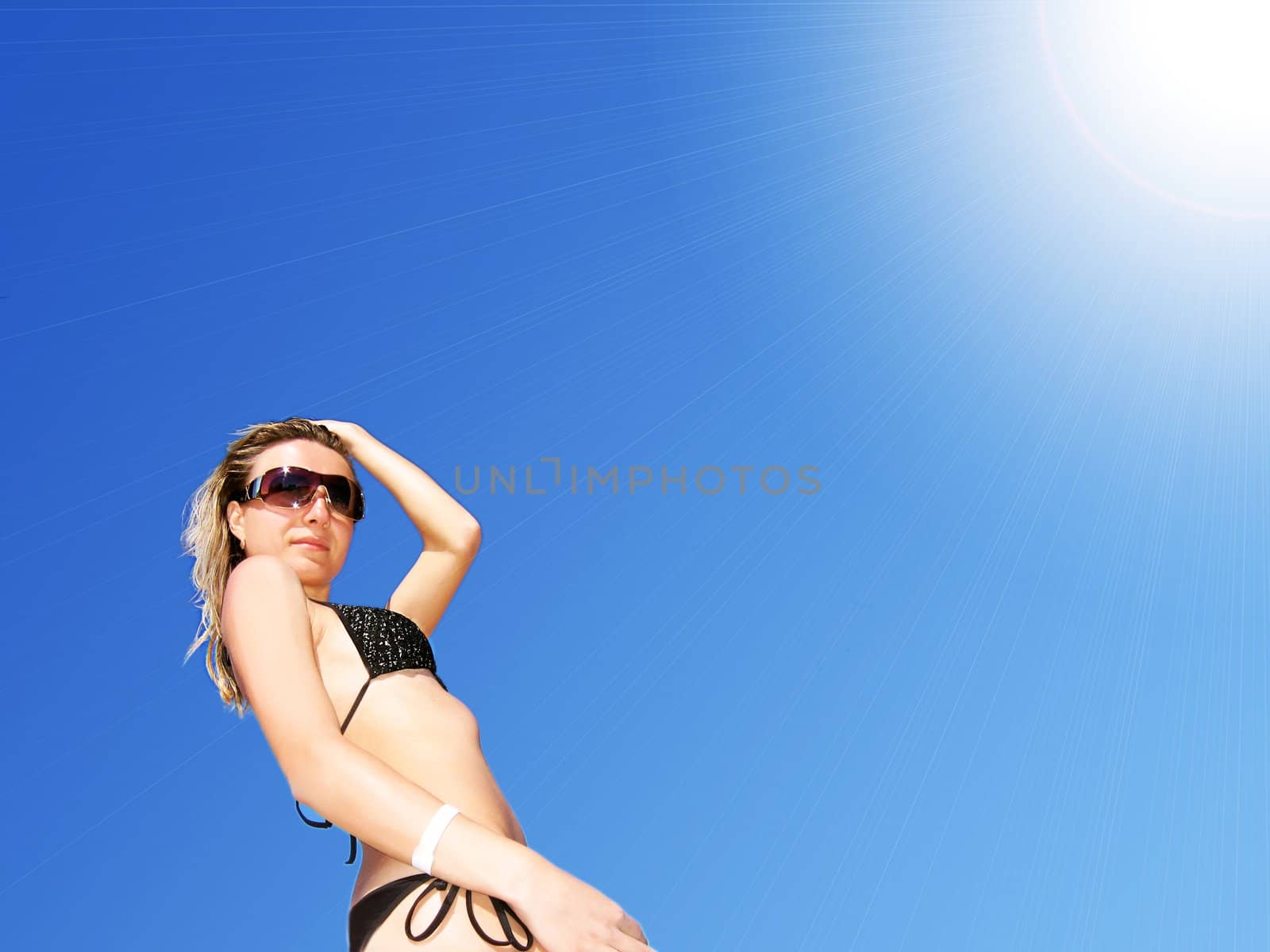 Woman in bikini against bright sun over blue sky