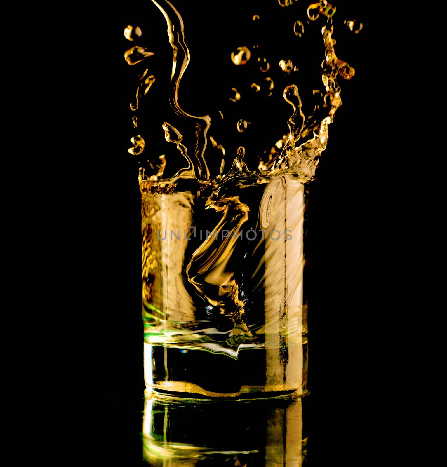 Glass of whisky on a black background. Spray and splash.