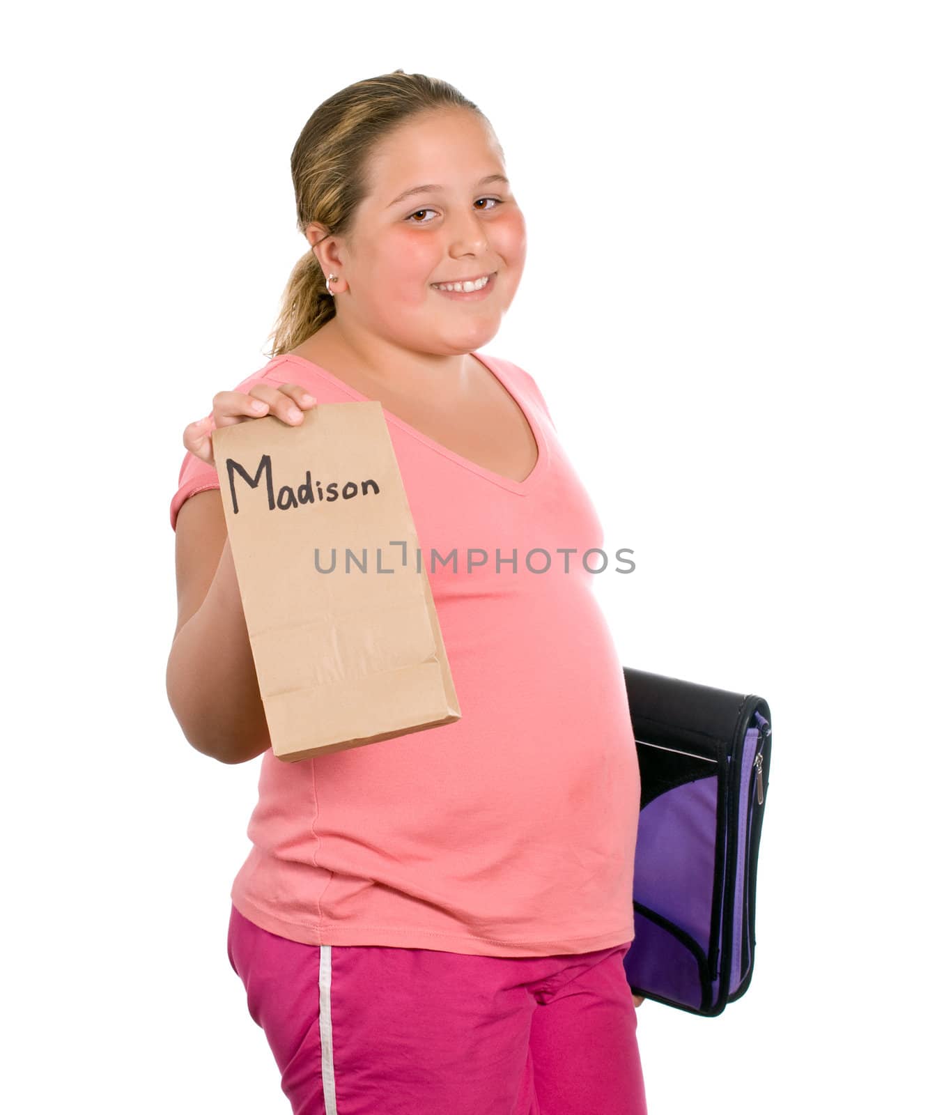 A young girl holding up her lunch for school, isolated against a white background with a fake name on the lunch bag