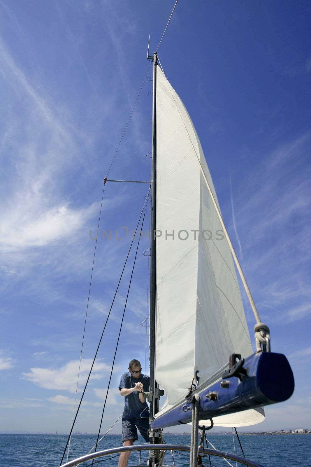 Sailor in sailboat rigging the sails by lunamarina