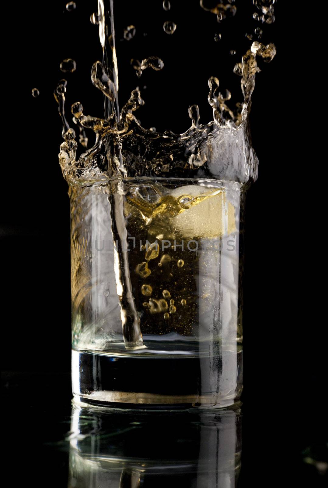 Glass of whiskey on a black background. Whiskey splash in a glass. Whiskey with ice.